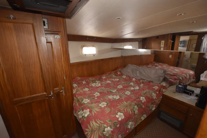 Slide: The Image of 1987 Hatteras SportFish cabin with floral bedspread, wooden cabinetry, and small windows. - 23