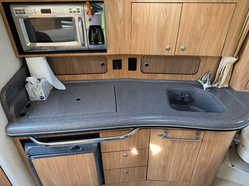 Slide: The Image of 2006 Sea Ray 320 Sundancer galley with microwave, sink, and storage cabinets. - 20