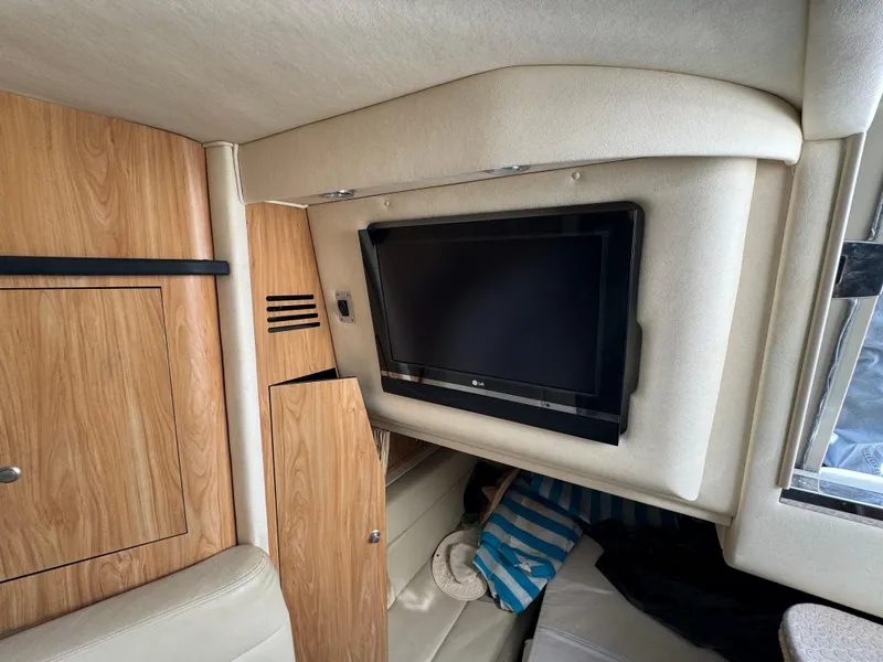 Slide: The Image of Interior of 2006 Sea Ray 320 Sundancer with mounted TV and wooden cabinetry. - 24