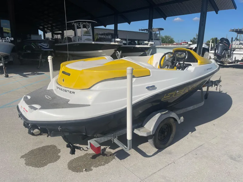 Slide: The Image of 2010 Sea-Doo 150 Speedster boat with yellow and white design on a trailer. - 2