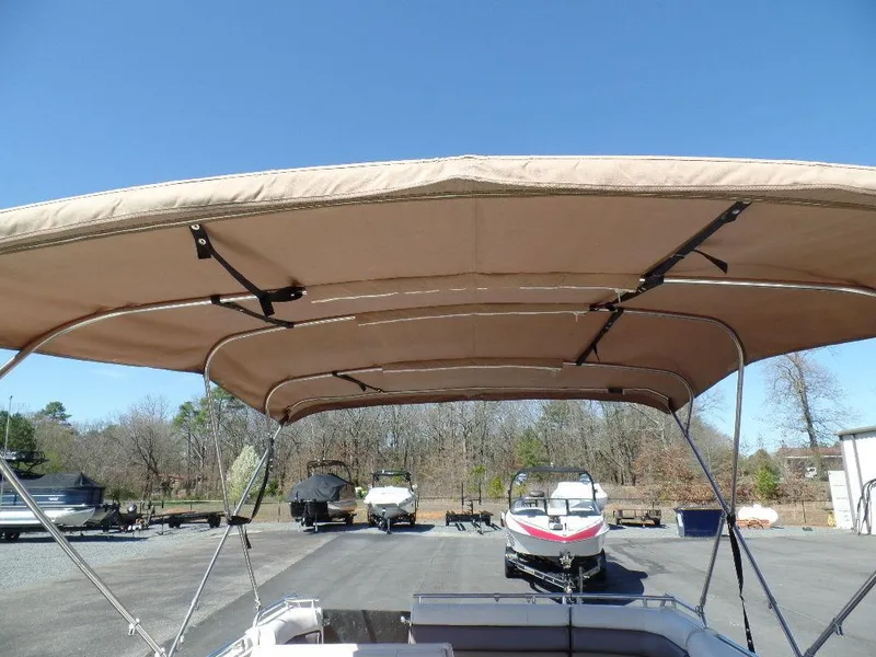 Slide: The Image of 1996 Hurricane Fun Deck boat with tan canopy in a parking lot. - 18