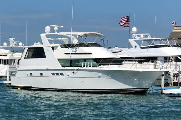 The Image of 1995 Hatteras 52 Cockpit Motor Yacht docked in a marina, with clear blue skies. - 0