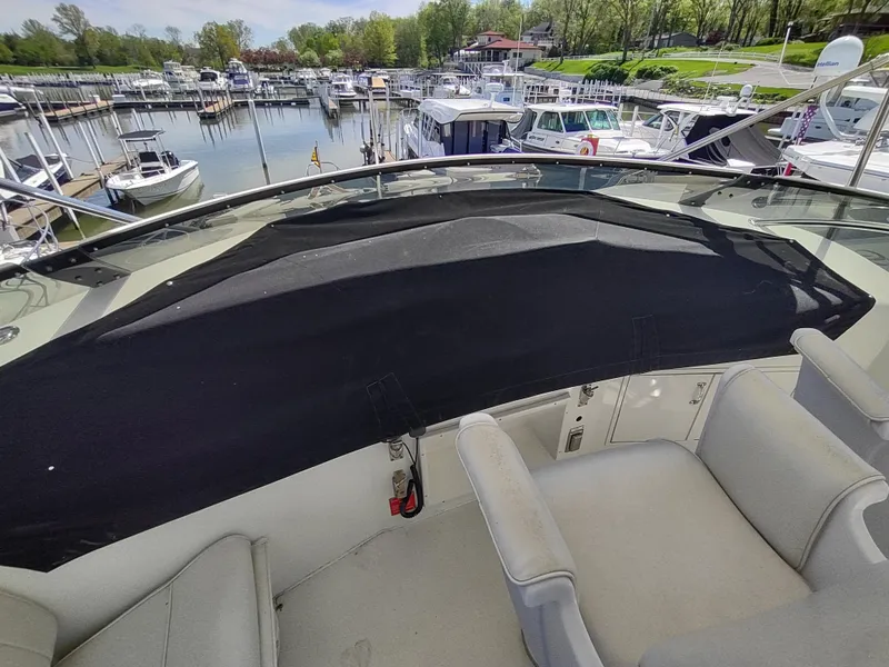 Slide: The Image of 1995 Hatteras 52 Cockpit Motor Yacht at marina, featuring spacious seating and covered helm. - 14