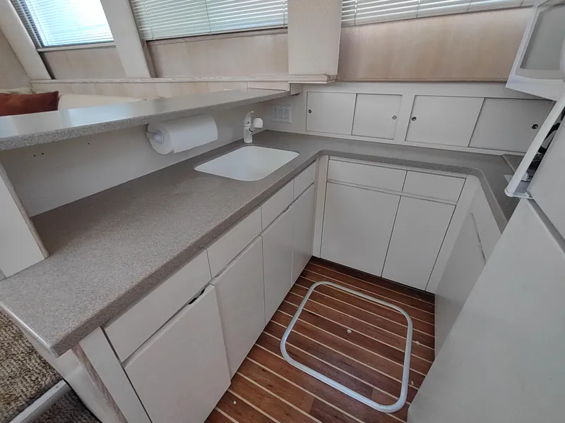Slide: The Image of 1995 Hatteras 52 Cockpit Motor Yacht kitchen with white cabinets and wood flooring. - 20