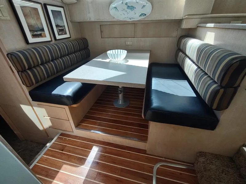 Slide: The Image of 1995 Hatteras 52 Cockpit Motor Yacht interior with striped seating and wooden flooring. - 21