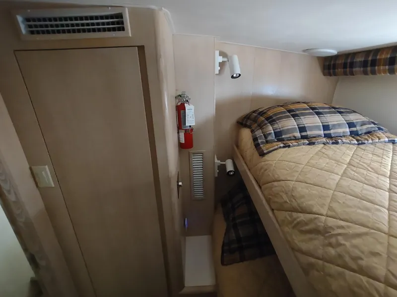 Slide: The Image of 1995 Hatteras 52 Cockpit Motor Yacht cabin with bunk beds and plaid bedding. - 27