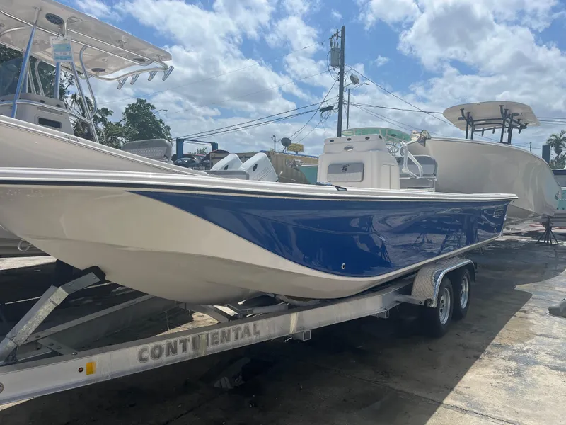 Slide: The Image of 2024 Carolina Skiff 25 LS boat on a trailer under a partly cloudy sky. - 1