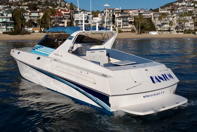 Slide: The Image of 1990 Tempest Offshore Sport Yacht cruising near a coastal residential area. - 1
