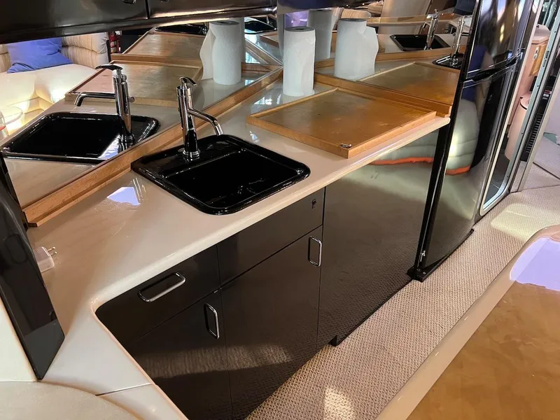 Slide: The Image of 1990 Tempest Offshore Sport Yacht kitchen with black sink, mirrored backsplash, and wooden cutting boards. - 26