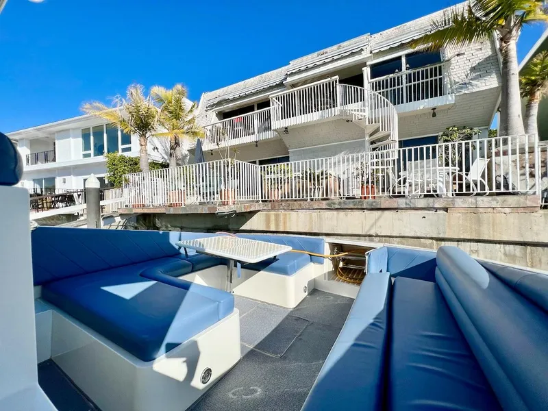 Slide: The Image of 1990 Tempest Offshore Sport Yacht docked near waterfront homes with blue seating and table. - 7