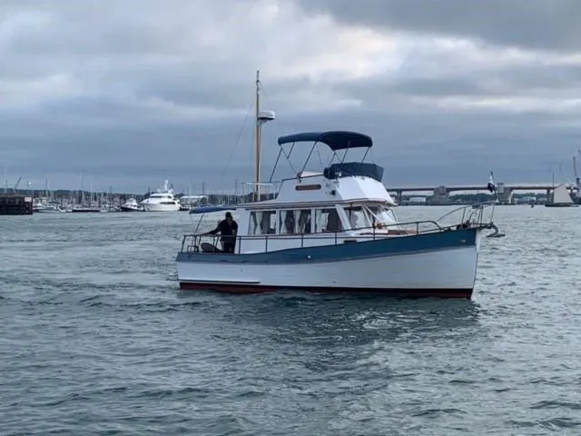 The Image of 1972 Grand Banks Trawler cruising in a harbor under cloudy skies. - 0