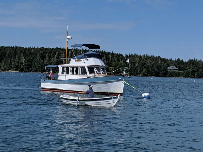 Slide: The Image of 1972 Grand Banks Trawler anchored in scenic lake with rowboat nearby. - 21