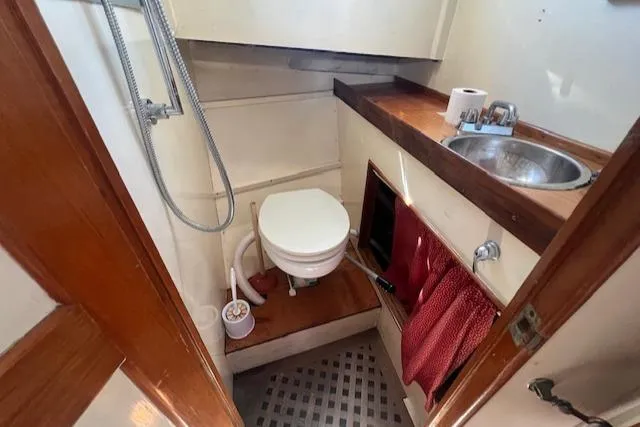 Slide: The Image of 1972 Grand Banks Trawler bathroom with toilet, sink, and showerhead. - 3