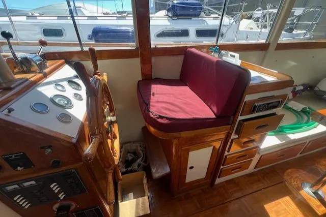 Slide: The Image of 1972 Grand Banks Trawler helm with wooden wheel, gauges, and maroon cushioned seat. - 5