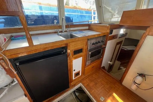 Slide: The Image of 1972 Grand Banks Trawler kitchen with wood cabinetry, sink, stove, and refrigerator. - 7