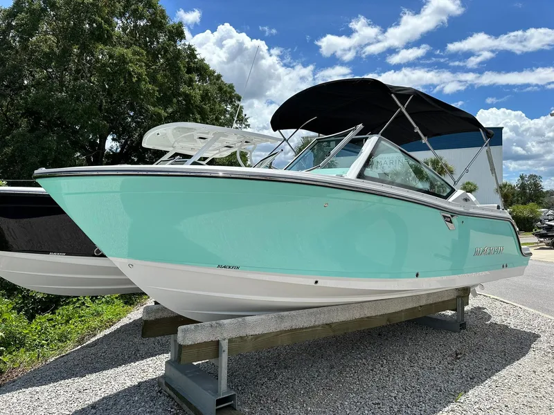 The Image of 2024 Blackfin 232 DC boat on trailer, turquoise hull, parked outdoors. - 0