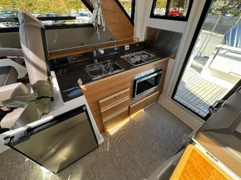 Slide: The Image of 2024 Cutwater C-288 C LE boat interior kitchen with stove, sink, and microwave. - 9