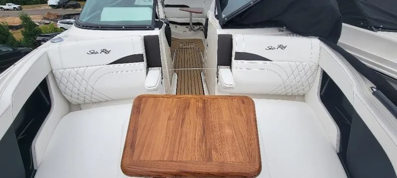 Slide: The Image of 2024 Sea Ray SLX 260 boat interior with wooden table and white seating. - 16