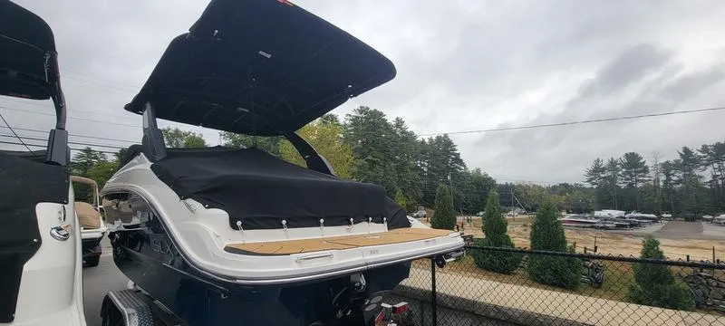 Slide: The Image of 2024 Sea Ray SLX 260 boat with black cover, parked outdoors. - 2