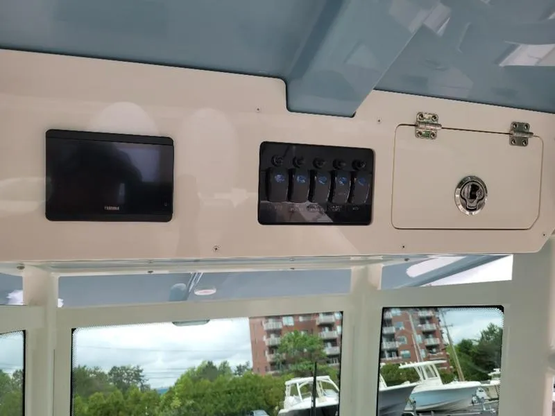 Slide: The Image of Control panel and storage compartment on a 2025 Sailfish 272 CC boat. - 27