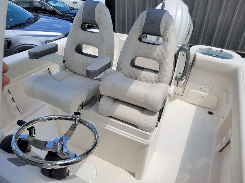 Slide: The Image of 2025 Sailfish 241 CC boat interior with dual captain's chairs and steering wheel. - 13