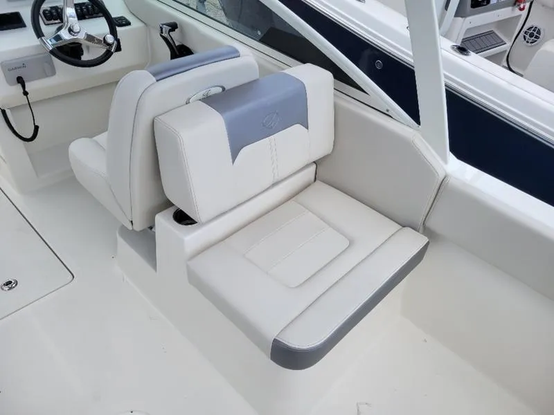 Slide: The Image of 2025 Sailfish 236 DC boat interior with seating and storage, docked by the water. - 13