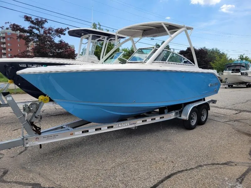 Slide: The Image of 2025 Sailfish 236 DC boat interior with cushioned seating and speakers, docked by the water. - 4