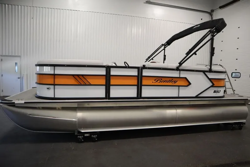 Slide: The Image of 2024 Bentley Pontoons 203 Bolt Tri-Toon in showroom, featuring sleek design and vibrant orange accents. - 8