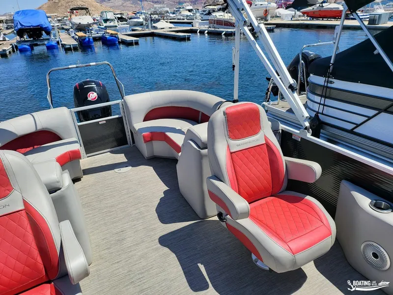 Slide: The Image of 2021 Bennington L25 Stern Radius pontoon boat with red and gray seating at a marina. - 12