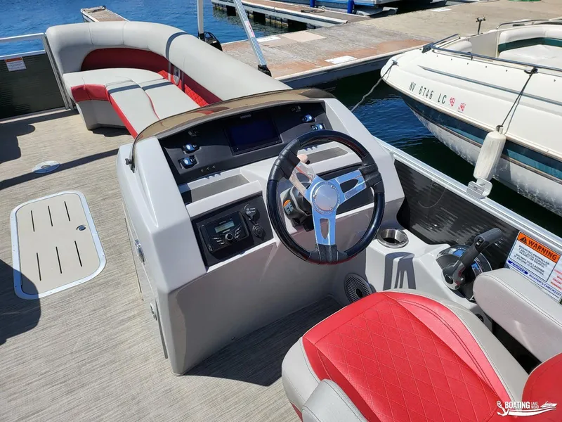 Slide: The Image of 2021 Bennington L25 Stern Radius boat interior with steering console and red seating. - 13