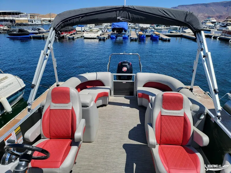Slide: The Image of 2021 Bennington L25 Stern Radius pontoon boat at marina, featuring red and gray seating. - 9