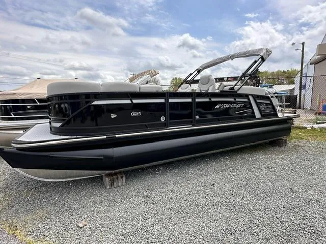 Slide: The Image of 2024 Starcraft SLS 3 Q DH pontoon boat on gravel lot under cloudy sky. - 0
