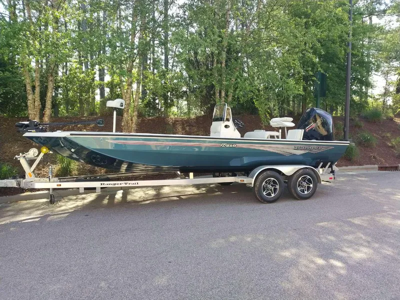 Slide: The Image of 2024 Ranger RB210 boat on a trailer in a wooded area. - 3