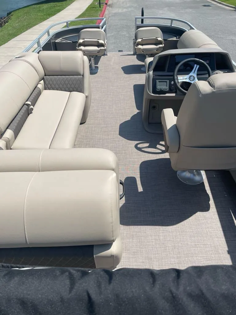 Slide: The Image of 2024 Sun Tracker Fishin' Barge 22 DLX interior with beige seating and steering console. - 4