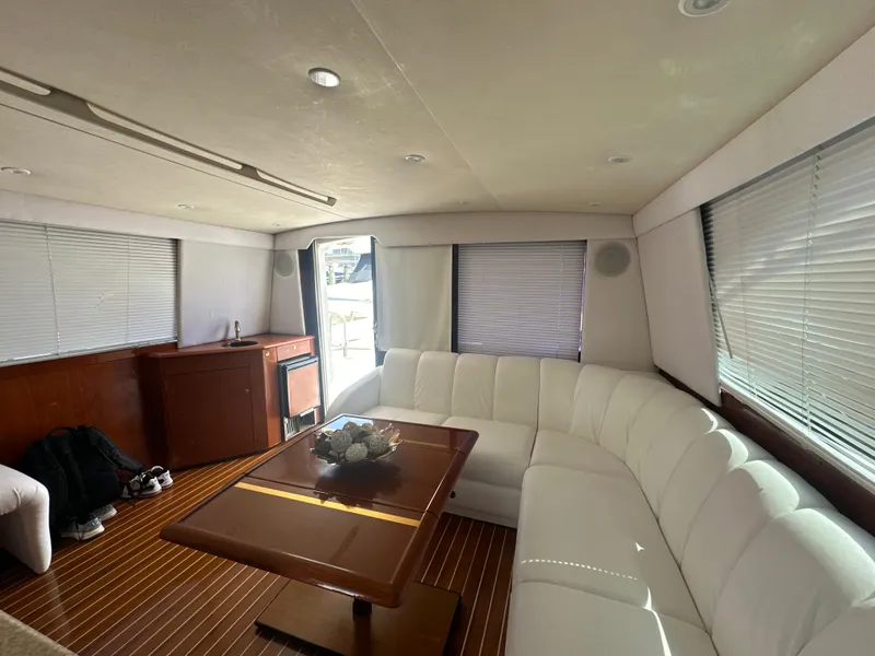 Slide: The Image of Interior of a 1999 Ocean 45 Super Sport yacht with white leather seating and wooden table. - 15