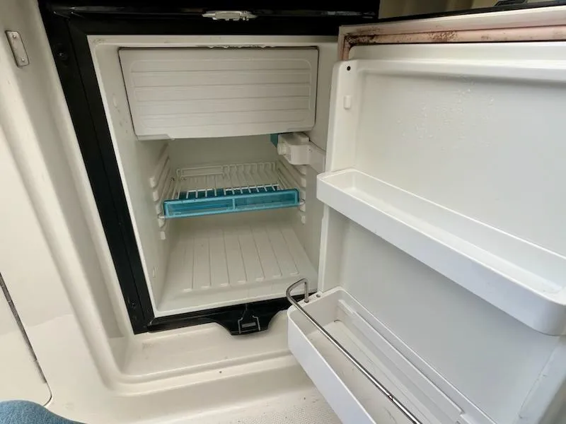 Slide: The Image of Open refrigerator inside 2012 Sea Ray 330 Sundancer boat, showing empty shelves and door compartments. - 13