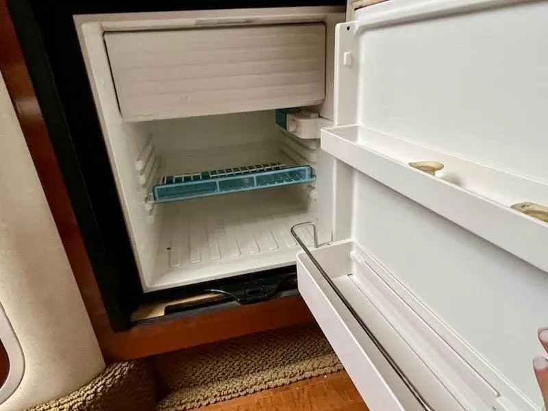 Slide: The Image of Open refrigerator inside a 2012 Sea Ray 330 Sundancer boat, showing empty shelves. - 27