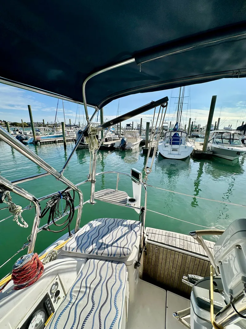 Slide: The Image of 2014 Hunter 33 sailboat docked at marina, featuring cockpit view and surrounding boats. - 20