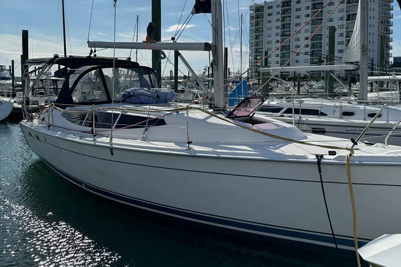 Slide: The Image of 2014 Hunter 33 sailboat docked at marina with modern buildings in background. - 5