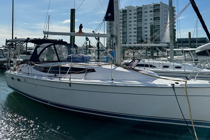 Slide: The Image of 2014 Hunter 33 sailboat docked at marina with modern buildings in background. - 6