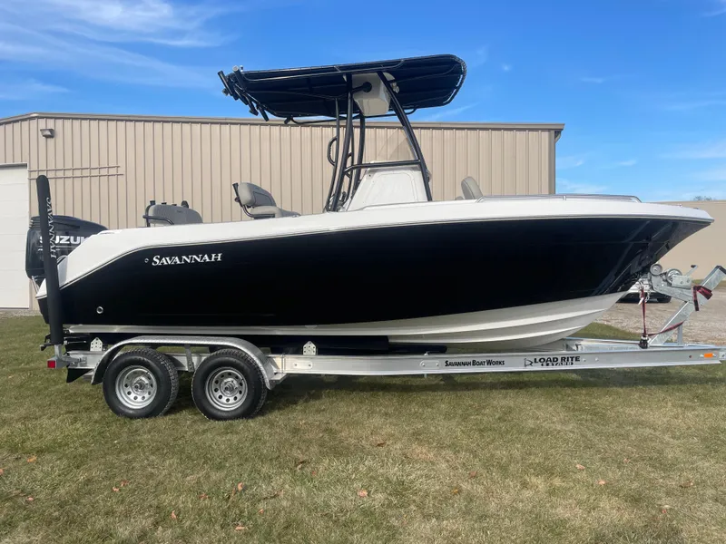 Slide: The Image of 2024 Savannah 2200 Offshore boat on trailer, black and white hull, parked on grass. - 8