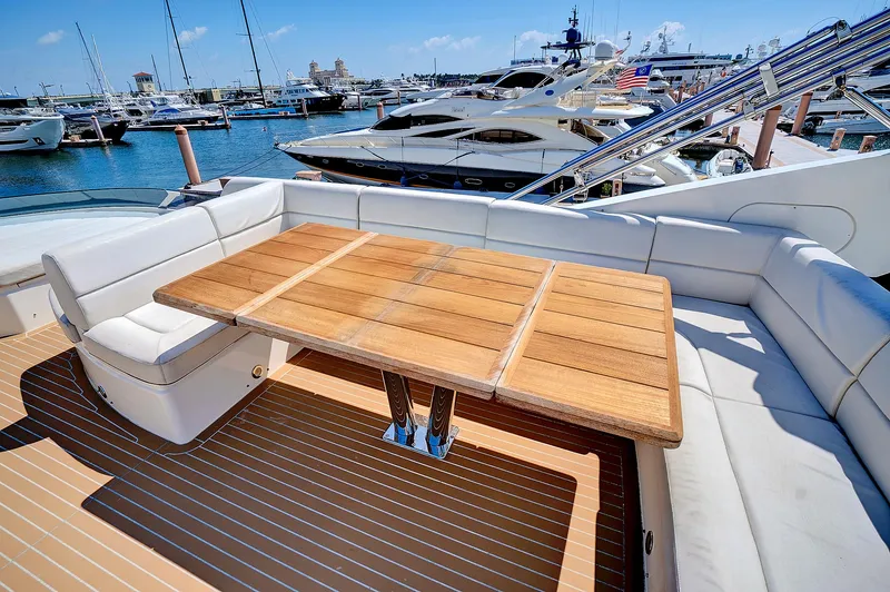 Slide: The Image of Sunseeker 68 Sport Yacht 2017, luxurious deck with wooden table and white seating, docked at marina. - 24