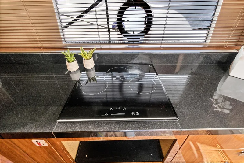 Slide: The Image of Modern kitchen on 2017 Sunseeker 68 Sport Yacht with sleek black countertop and electric stove. - 47