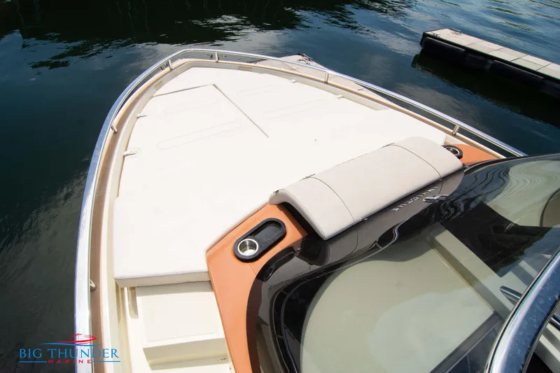 Slide: The Image of 2024 Invictus GT320S boat bow with cushioned seating, docked on calm water. - 45