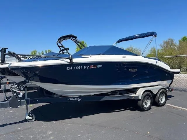Slide: The Image of 2018 Sea Ray SPX 190 boat on a trailer, blue hull, parked outdoors. - 1