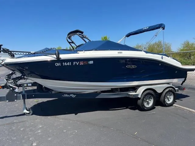 Slide: The Image of 2018 Sea Ray SPX 190 boat on a trailer, blue hull, parked outdoors. - 2