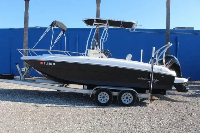Slide: The Image of 2018 Bayliner Element F21 boat on trailer, parked near blue wall. - 8