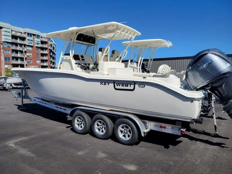 Slide: The Image of 2025 Key West 291 FS boat on trailer, parked outdoors, clear blue sky. - 4