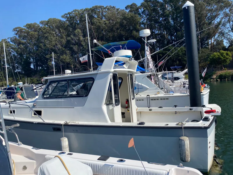 The Image of 1986 Luhrs Alura boat docked in a marina, surrounded by other vessels and trees. - 0