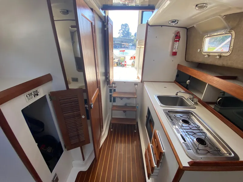 Slide: The Image of 1986 Luhrs Alura boat interior with kitchenette, wooden flooring, and compact design. - 16
